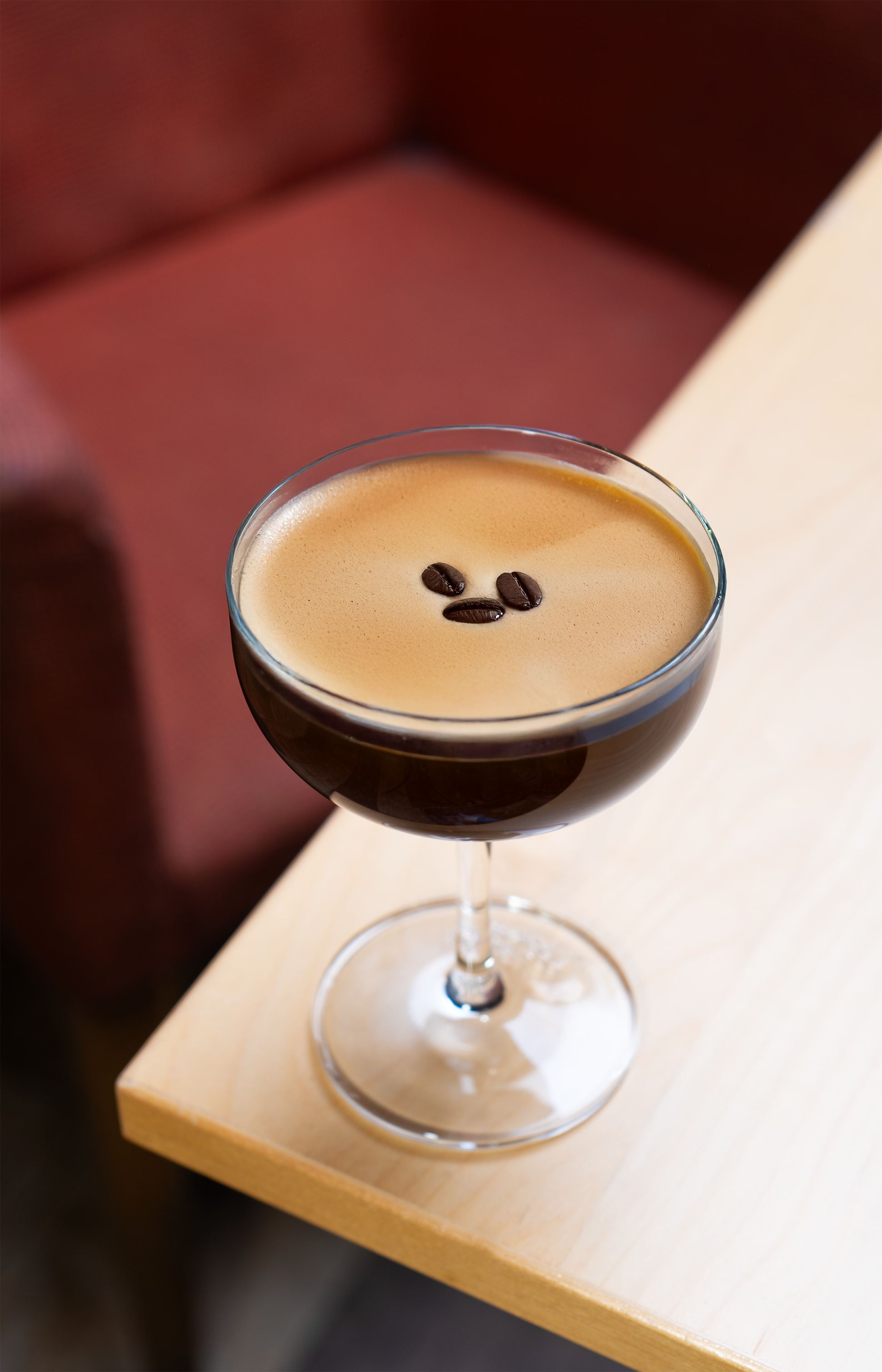 Glass of an espresso martini on the edge of a table.