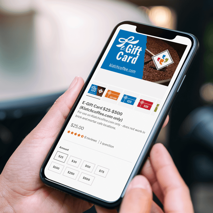 Close-up photo of someone holding a smartphone displaying the gift card page of the Klatch Coffee website.