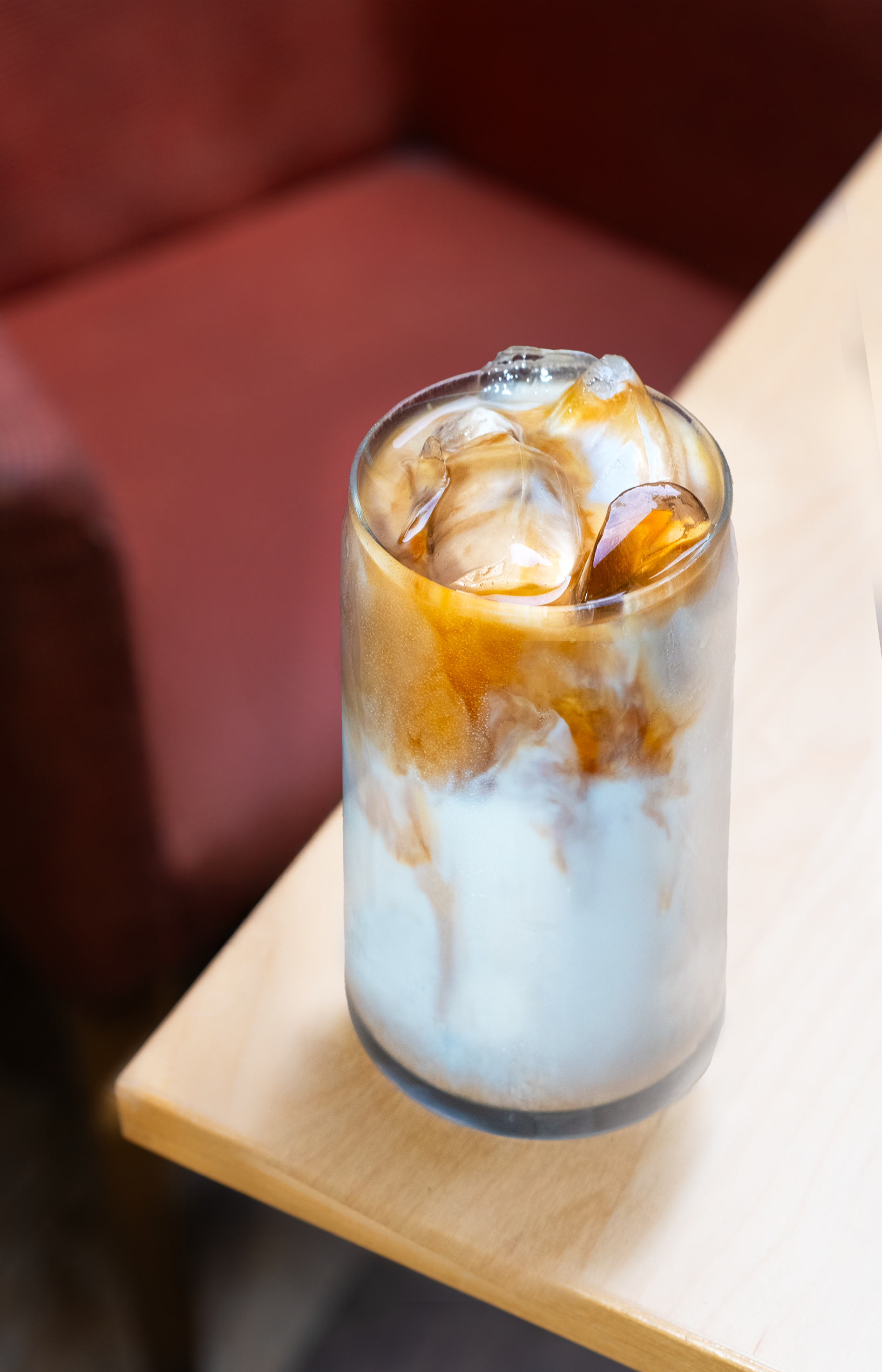 Glass of a flavored latte on the edge of a table. 